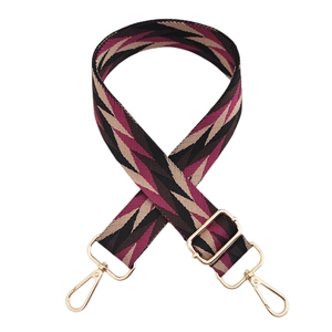 Macro detail of geometric patterned woven wide shoulder strap with gold metal swivel clasps