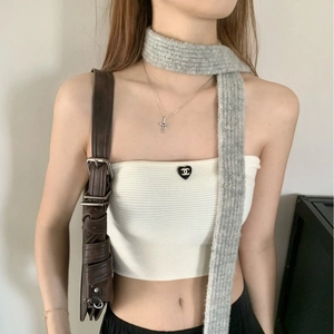 Macro shot of white knitted tube top featuring a black heart motif and luxury logo