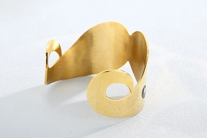 Detail of gold matte stainless steel open cuff bracelet with abstract geometric cutouts