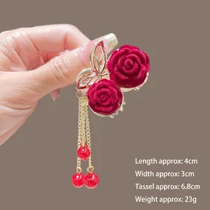 Détail d'une pince à cheveux rose en velours rouge avec franges dorées et perles