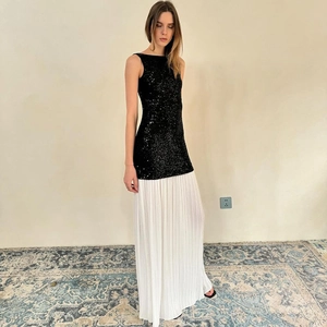Detail of a two-tone dress with black sequin bodice and white pleated long skirt