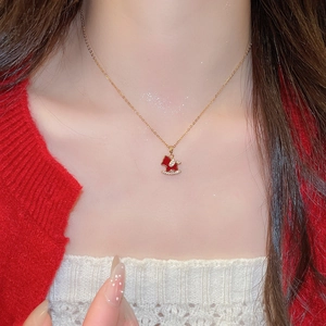 Detail of gold-plated rocking horse pendant necklace with red enamel and pavé zircons