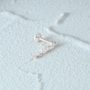 Macro shot of silver 925 cartilage stud with flat back and three sparkling zircons on a chain