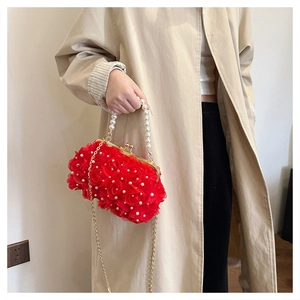 Détail du sac de soirée rose rouge avec pétales 3D, poignée en perles et chaîne dorée