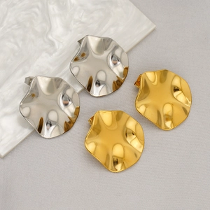 Vue détaillée de boucles d'oreilles irrégulières en acier doré et argenté sur un support