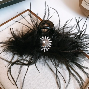 Détail de la pince à cheveux en plumes noires avec fleur en strass de cristal scintillant