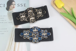Close-up of wide elastic waist belts featuring sparkling rhinestone floral buckles for women.