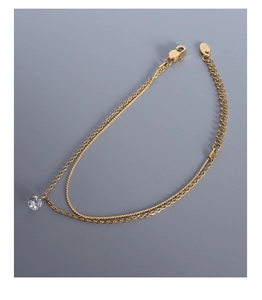 Detail of double-layer 18k gold plated titanium bracelet with a round zircon stone