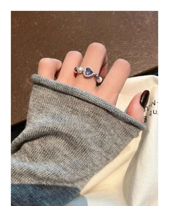 Detail of elegant ring featuring heart purple gemstone and white pearl on hand