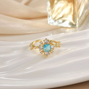 Macro detail of gold ring featuring a blue square gemstone surrounded by clear crystals