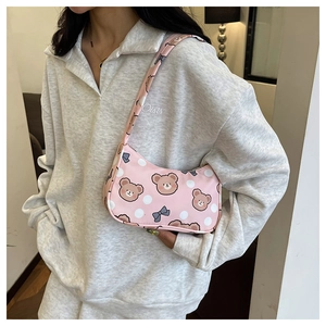 Pink cartoon teddy bear shoulder bag with blue bow and polka dots shown on model