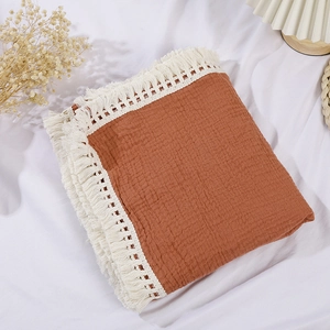 Detailed view of terracotta baby cotton gauze blanket with elegant white fringe lace trim