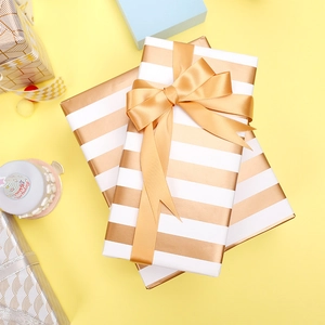 Gold and white striped gift wrapping paper roll with elegant gold satin ribbon and bow