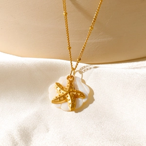 Gros plan d'un pendentif étoile de mer et coquillage sur un tissu en soie blanche