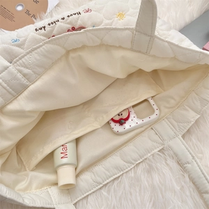 Close-up of quilted heart pattern and interior pocket of a white cat embroidery tote bag
