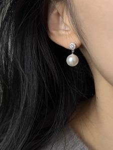 Close-up of elegant s925 silver stud earrings with white pearls and sparkling zircons