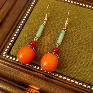 Retro style orange persimmon drop earrings with green jade beads on dark green stand