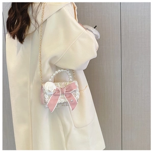 Girls tweed shoulder bag with pink bow and pearl handle worn by model in casual scene