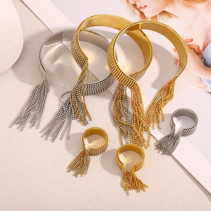 Close-up of 18K gold and silver beaded tassel bracelets and rings on a textured base