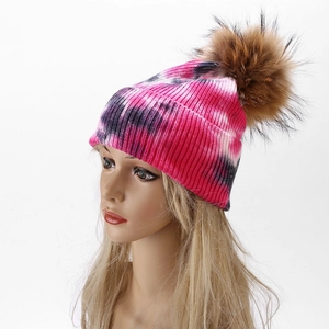Close-up of tie-dye knit beanie with pink and black patterns and fluffy pompom