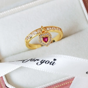 Close-up of golden heart pendant ring with pink zircon gemstone in a gift box