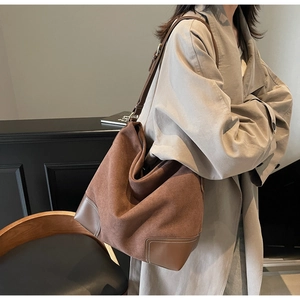 Detail of vintage dark brown suede tote bag with leather corners and white stitching