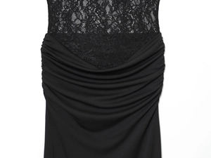Dettaglio delle cuciture in pizzo nero e dell'elegante tessuto a pieghe sull'abito