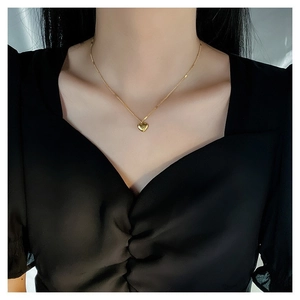Minimalist gold heart pendant necklace on woman wearing a stylish black square neck top
