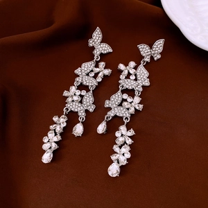 Close-up of crane earrings with silver butterfly, flower motifs and sparkling crystals