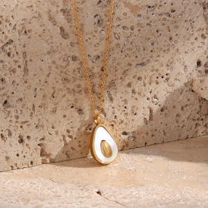 Detail showing a gold-plated avocado shell pendant necklace on a beige textured stone