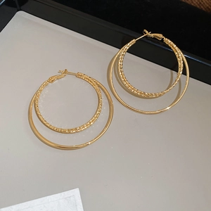 Detail of 18k gold plated double hoop earrings with textured inner ring on a display tray