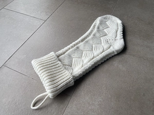Detail of white cable knit Christmas stocking with thick fold-over cuff and hanging loop
