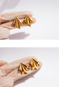 Macro detail of golden irregular geometric stud earrings with artistic pleated metal texture