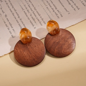 Détail de boucles d'oreilles vintage en bois et résine ambrée sur des pages de livre