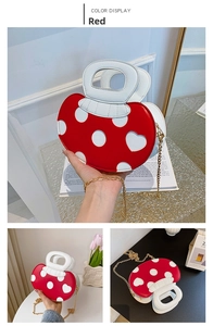 Detail of red mushroom handbag with white heart patterns and gold chain strap