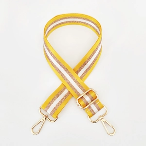 Detail of yellow and gold striped nylon bag strap with polished gold metal buckles