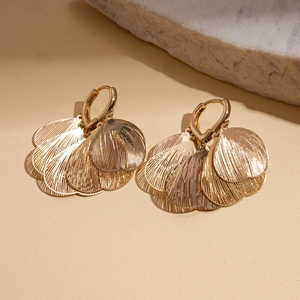 Detailed view of hollow gold heart petal earrings on a neutral stone display