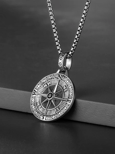 Detailed view of silver compass pendant with engraved directions on a box chain