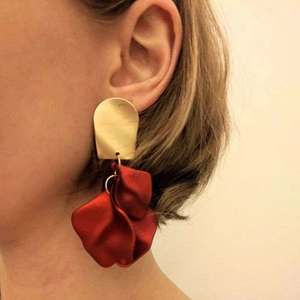 Fashionable gold metal studs with red layered petal drops on model's ear
