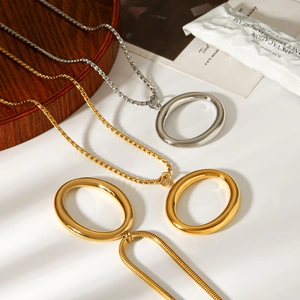 Close-up of polished oval pendants on gold and silver chain necklaces on a wooden tray