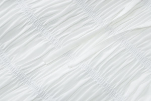 Vue macro du tissu plissé blanc et détail de lien sur une robe chic à col en V