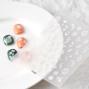 Macro shot of 5D white floral nail stickers and embossed leaf patterns on nail tips