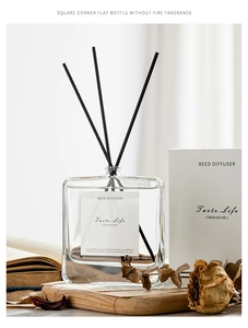 Detail view of square glass reed diffuser set with black sticks on a wooden tray