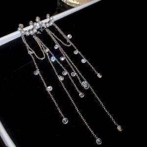 Detailed close-up of silver tassel earrings with pearls and crystals on black velvet
