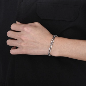 Nahaufnahme eines silbernen Gliederketten-Armbands aus Titanstahl am Handgelenk