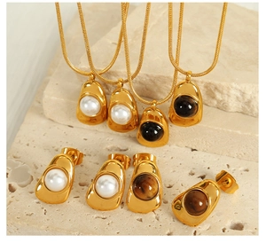Close-up of gold necklaces and stud earrings with pearls and tiger eye stones