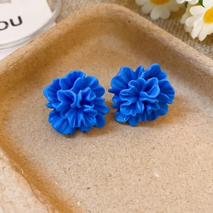 Vue macro de boucles d'oreilles fleurs en résine bleu Klein avec pétales sur un plateau