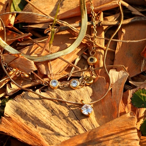 Three-layer gold titanium steel necklace with zircon pendants on autumn leaf background