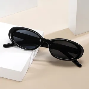 Fashionable black oval frame sunglasses with dark lenses on a white minimalist cube