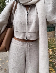 Detail of beige knitted zip-up jacket and wide-leg trousers set with matching scarf